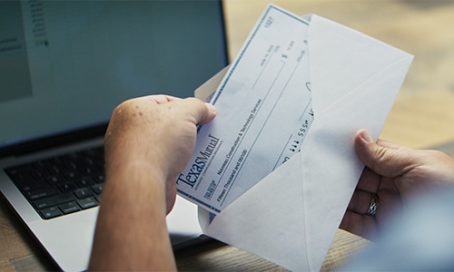 Hand taking a dividend check out of an envelope