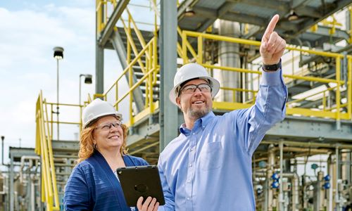 Man and woman at a plant looking up.